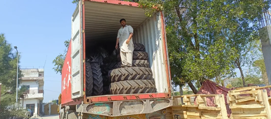 Tractor tyres and machinery being prepared inside a shipping container